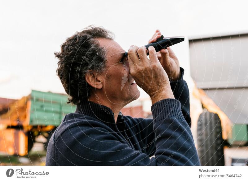 Man looking through refractometer at winery color image colour image Spain outdoors location shots outdoor shot outdoor shots day daylight shot daylight shots