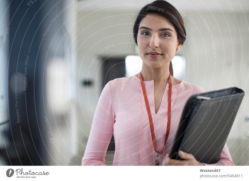 Portrait of young woman holding folder on the corridor in office file folders portfolio portfolios files Corridor Corridors Hallways Halls females women Office