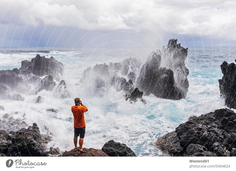 USA, Hawaii, Big Island, Laupahoehoe Beach Park,Man taking pictures of breaking surf at the rocky coast 50-55 years 50 to 55 years breaking wave breaking waves