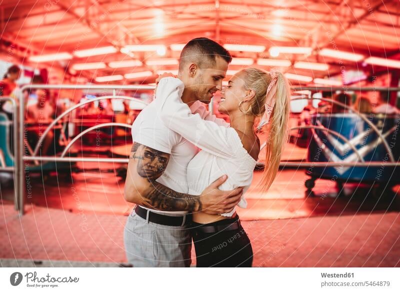 Romantic young couple embracing while standing at amusement park 20-25 years 20 to 25 years young women young woman 25-30 years 25 to 30 years young man