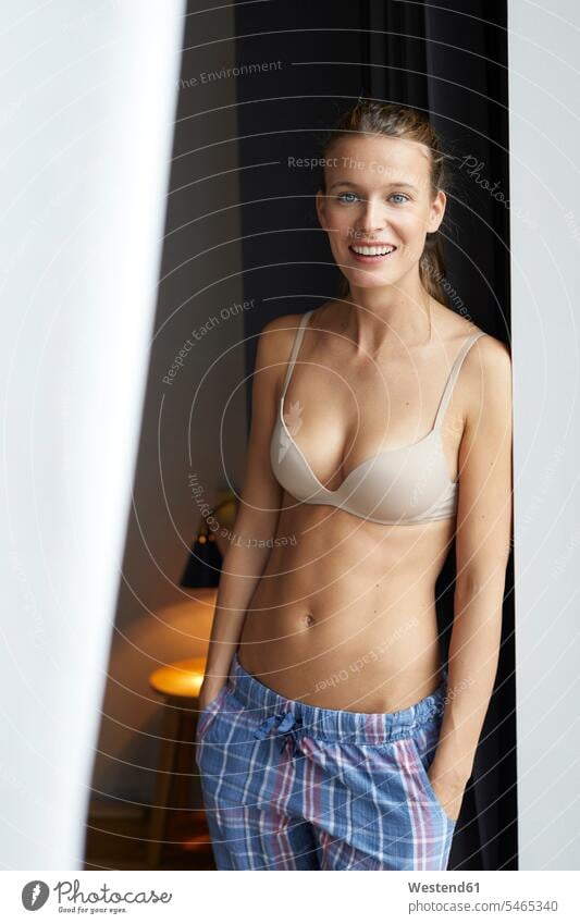 Portrait of smiling young woman standing wearing bra and pyjama pants stock  photo