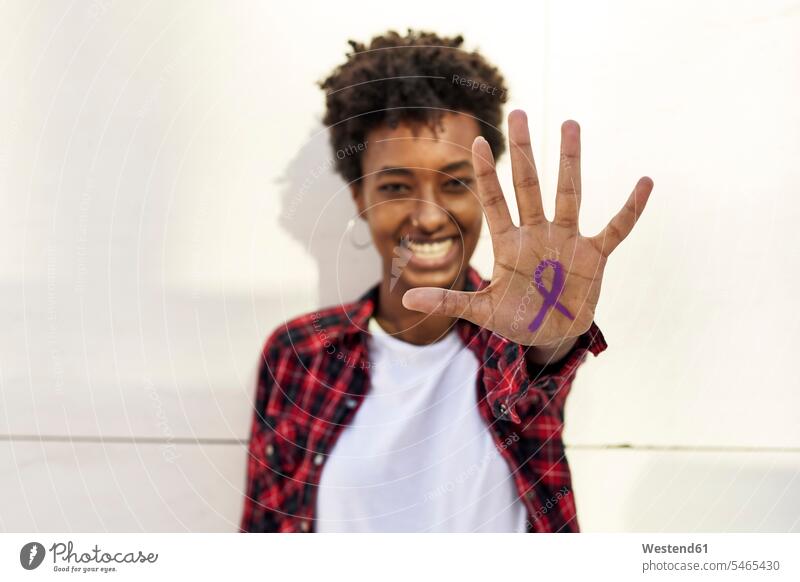 Happy young woman showing purple awareness symbol on palm against