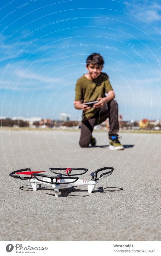 Boy flying drone boy boys males drones child children kid kids people persons human being humans human beings sky skies focus on foreground