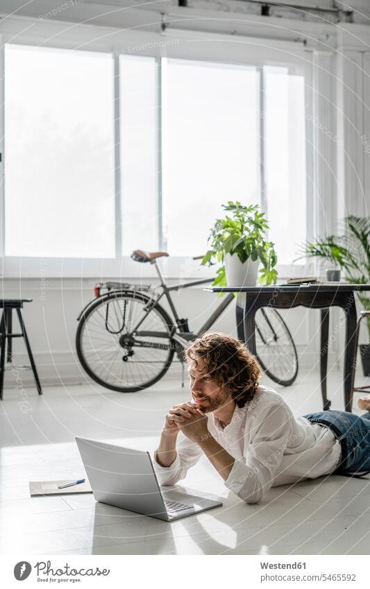 Smiling man lying on the floor at home using laptop human human being human beings humans person persons caucasian appearance caucasian ethnicity european 1