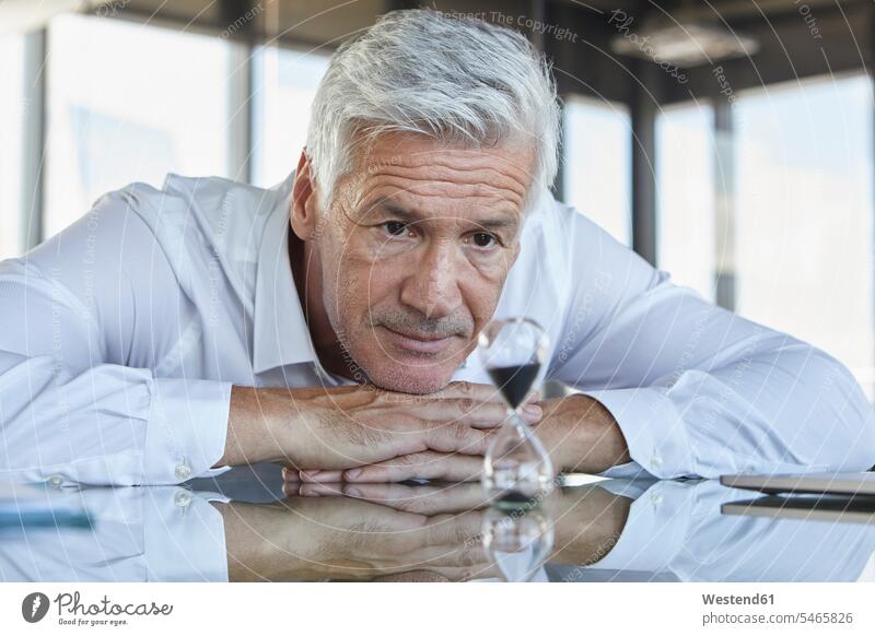 Businessman sitting at desk, watching hourglass desks looking looking at Hourglass Sand Glass Hourglasses Hour Glass Hour Glasses Sand Glasses Business man