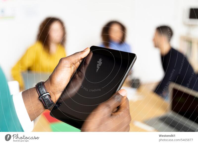 Close-up of businessman in office using tablet with colleagues in background human human being human beings humans person persons Mixed Race