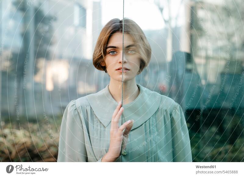 Portrait of woman with half of her face behind a glass windows glass panes shirts Retro retro revival Retro Styled Retro-Styled diffident reluctance reluctant
