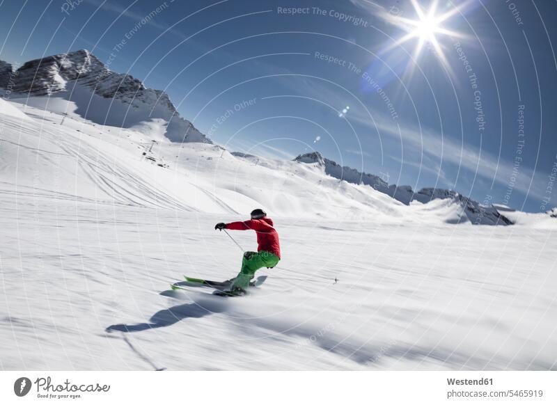 Germany, Bavaria, Garmisch-Partenkirchen, Sun shining over man skiing at Zugspitze outdoors location shots outdoor shot outdoor shots day daylight shot