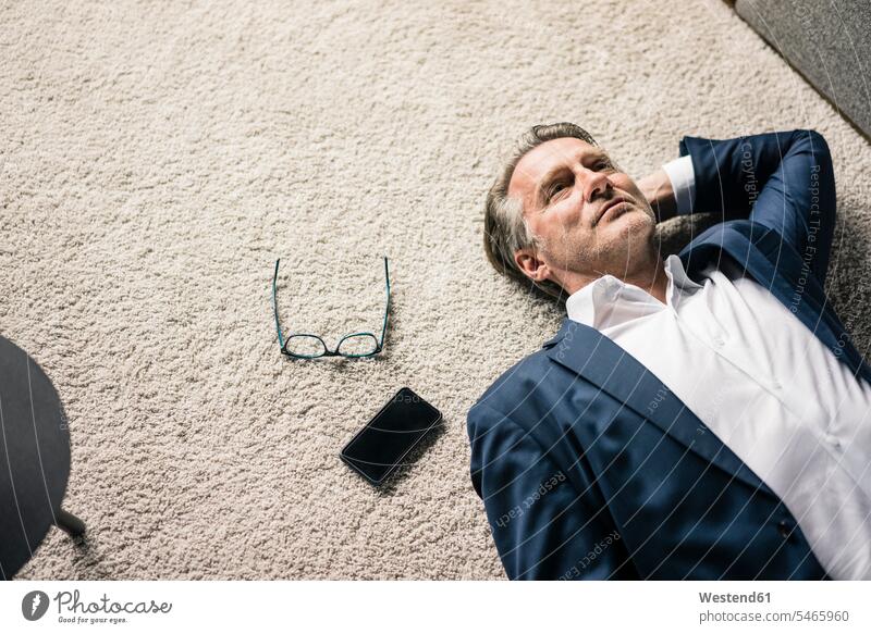 Mature businessman lying on carpet next to cell phone Businessman Business man Businessmen Business men laying down lie lying down carpets rug rugs