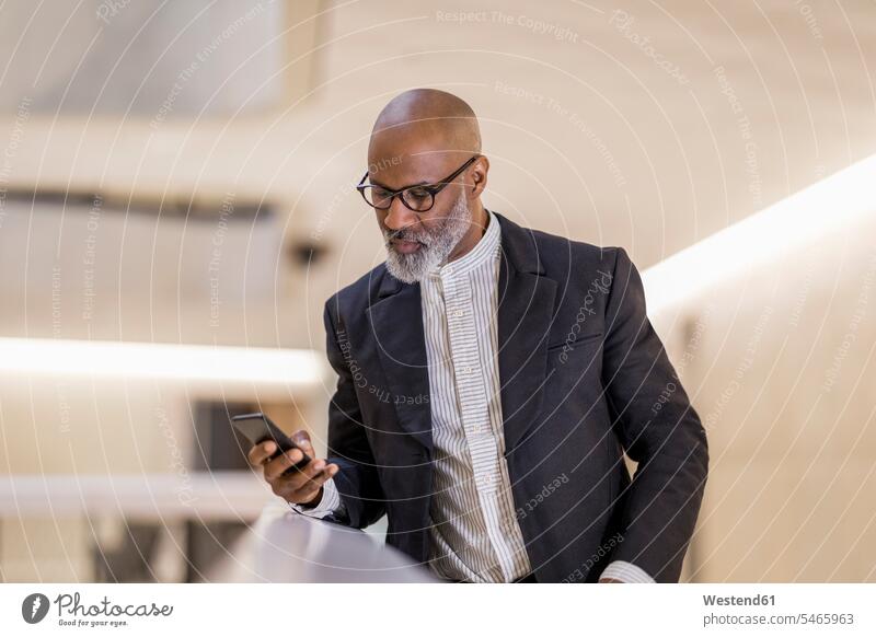 Portrait of bald mature businessman looking at cell phone Businessman Business man Businessmen Business men Smartphone iPhone Smartphones portrait portraits