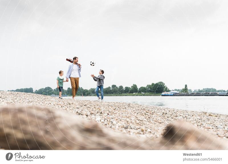 Happy father with two sons and football walking at the riverside soccer ball soccer balls footballs pa fathers daddy dads papa going manchild manchildren