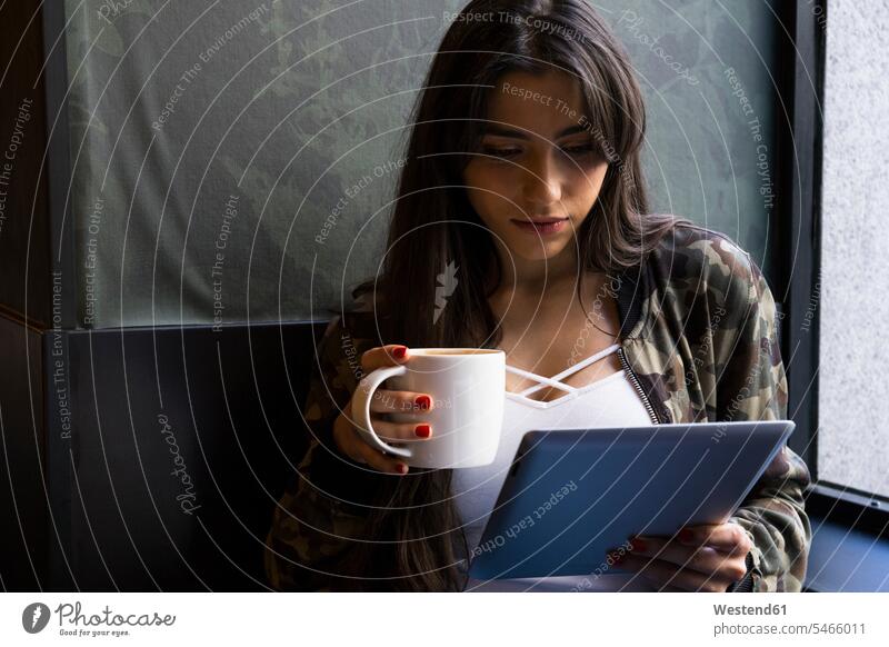 Young woman sitting in cafe with cup of coffee and using tablet friends mate female friend best friends bff together happy confident community hold contemplate