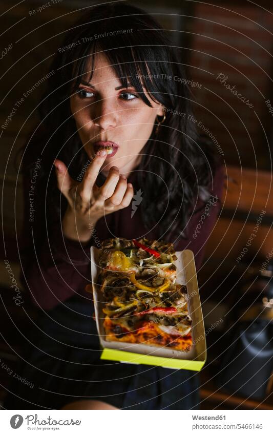 Young girl in the city eating a piece of pizza at night benches Seated sit in the evening enjoy enjoyment indulgence indulging savoring free time leisure time