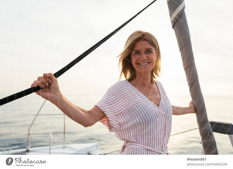 Mature woman on catamaran, watching sunset mature woman mature women sunsets sundown standing females Adults grown-ups grownups adult people persons human being