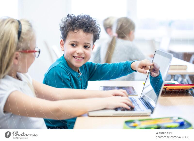 Schoolboy and schoolgirl using laptop together in class student pupils Laptop Computers laptops notebook schools Classroom class rooms Schoolroom classrooms