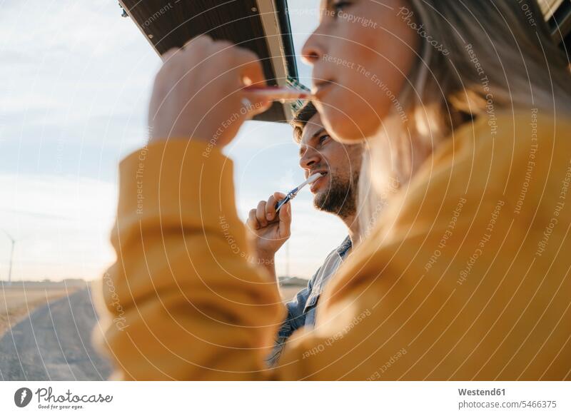 Couple brushing teeth in camper van in rural landscape Camper country countryside couple twosomes partnership couples landscapes scenery terrain motor vehicle