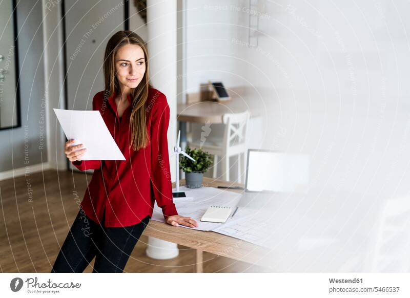 Woman in office holding paper with wind turbine model on table Occupation Work job jobs profession professional occupation business life business world