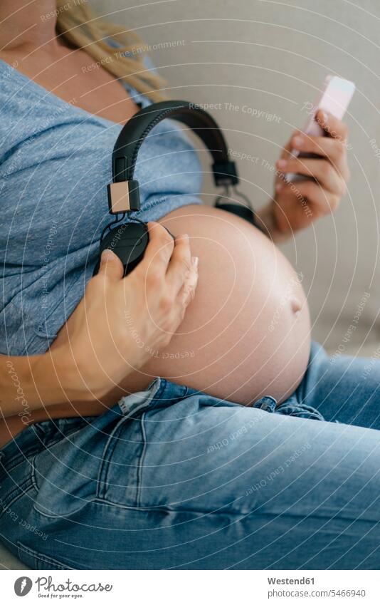 Mid section of pregnant woman holding headphones at her belly a