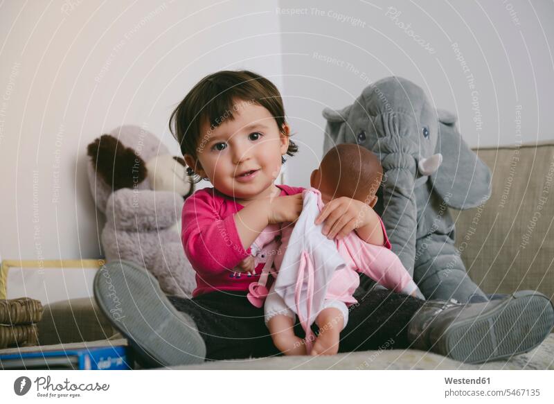 Portrait of smiling baby girl playing with doll at home portrait portraits baby girls female smile dolls babies infants people persons human being humans