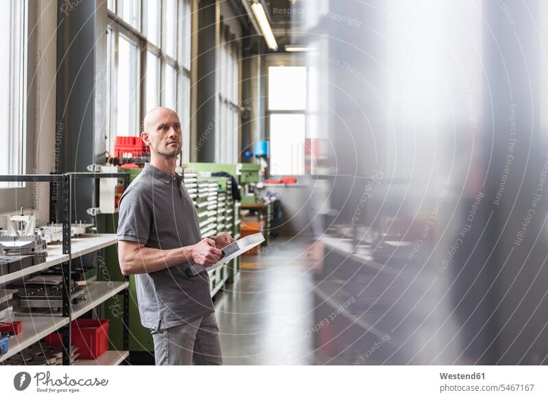 Man standing in modern factory holding product man men males products factories examining checking examine contemporary Adults grown-ups grownups adult people
