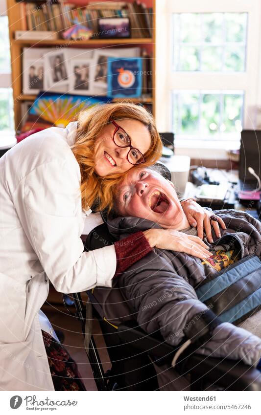 Female nurse embracing disabled man sitting at rehabilitation center color image colour image indoors indoor shot indoor shots interior interior view Interiors