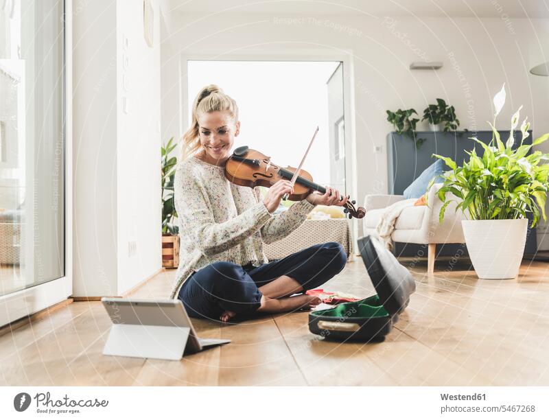 Woman with tablet sitting on the floor at home playing violin human human being human beings humans person persons celibate celibates singles solitary people