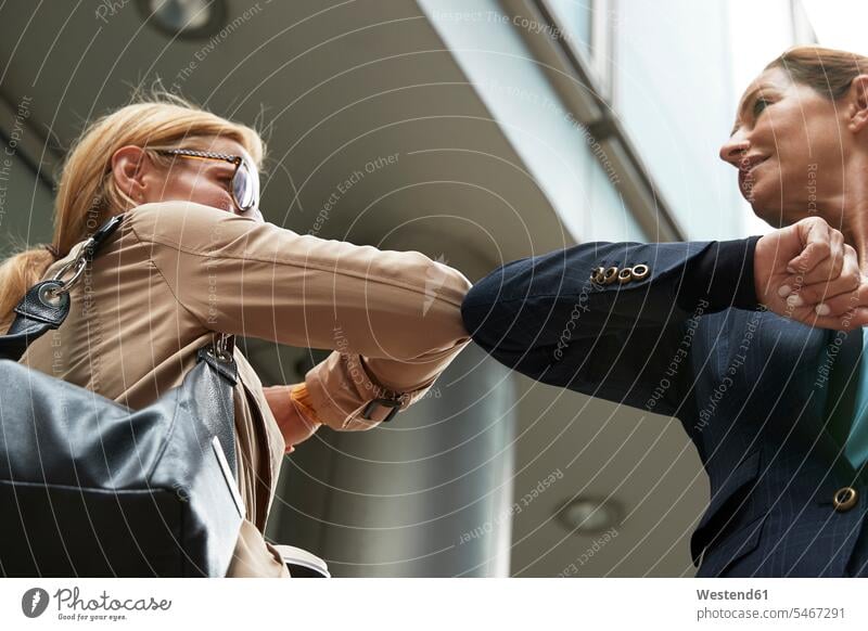 Smiling colleagues greeting with elbow bump while standing in city color image colour image outdoors location shots outdoor shot outdoor shots day daylight shot