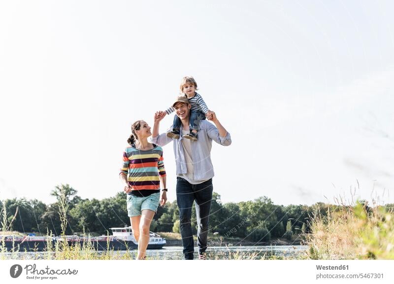 Happy family walking at the riverside on a beautiful summer day going happiness happy summer time summery summertime riverbank water's edge waterside shore