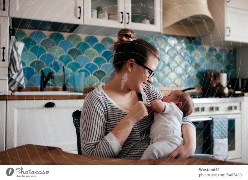 Portrait of a young woman with a baby at home Eye Glasses Eyeglasses specs spectacles hold cuddle snuggle snuggling smile Seated sit peaceable peaceful Secure