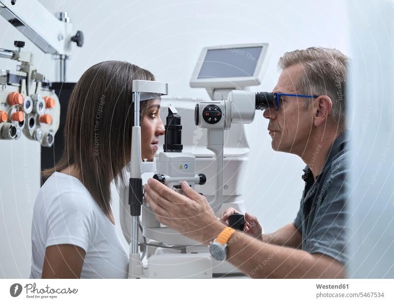 Optometrist examining young woman's eye patient checking Test testing Check examination examine examinations ophthalmologist eyesight Optometry patients illness