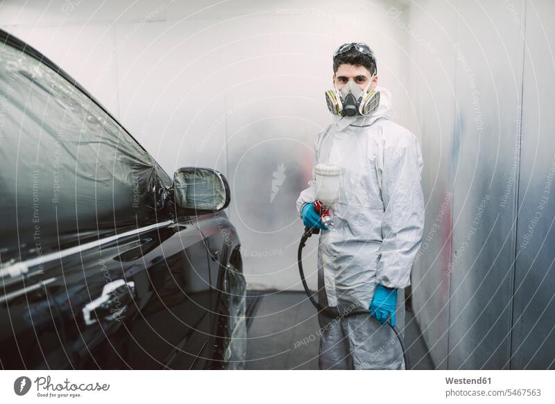 Auto painter inside a paint booth man men males paint booths Protection protecting worker blue collar worker workers blue-collar worker skill Ability skilled