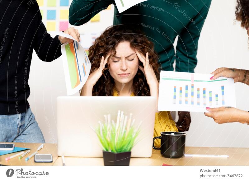 Stressed woman siting at desk in office surrounded by colleagues human human being human beings humans person persons Mixed Race mixed race ethnicity