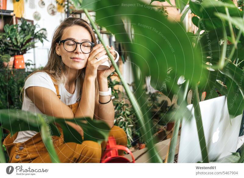 Young woman having a coffee break in a small gardening shop Occupation Work job jobs profession professional occupation computers Laptop Computer