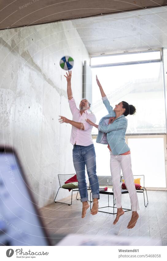 Casual businessman and businesswoman playing basketball in a loft Businessman Business man Businessmen Business men lofts basketballs businesswomen