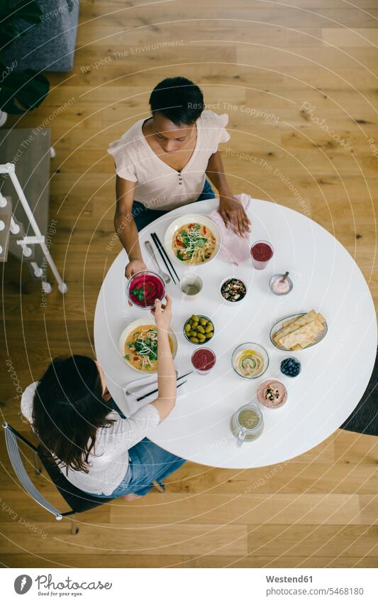 Two women sitting at table having a healthy meal friends mate female friend Drinking Glass Drinking Glasses Bowls dish dishes Plates Tables Dining Tables