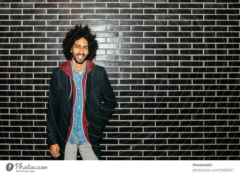 Portrait of a smiling young man standing at a black wall men males portrait portraits walls smile Adults grown-ups grownups adult people persons human being