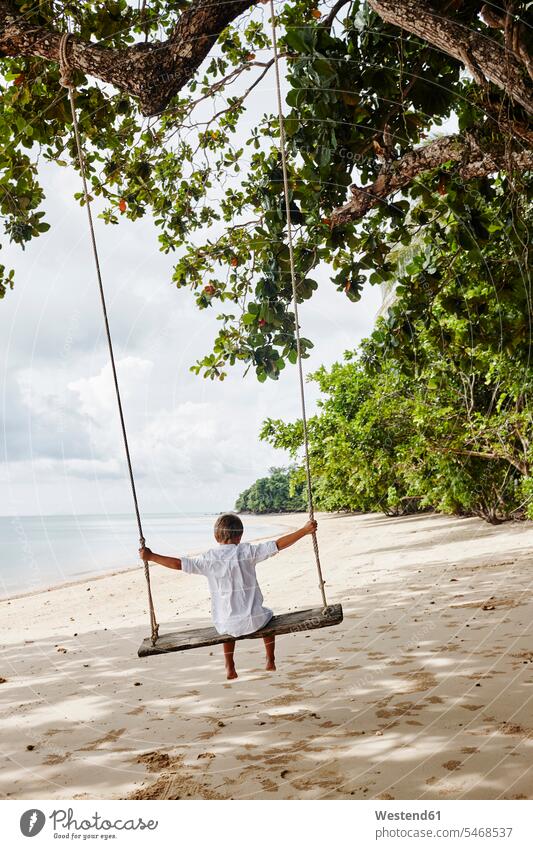 Thailand, Ko Yao Noi, boy on a swing on the beach beaches boys males swing set playground swing swingset swinging rock rocking child children kid kids people