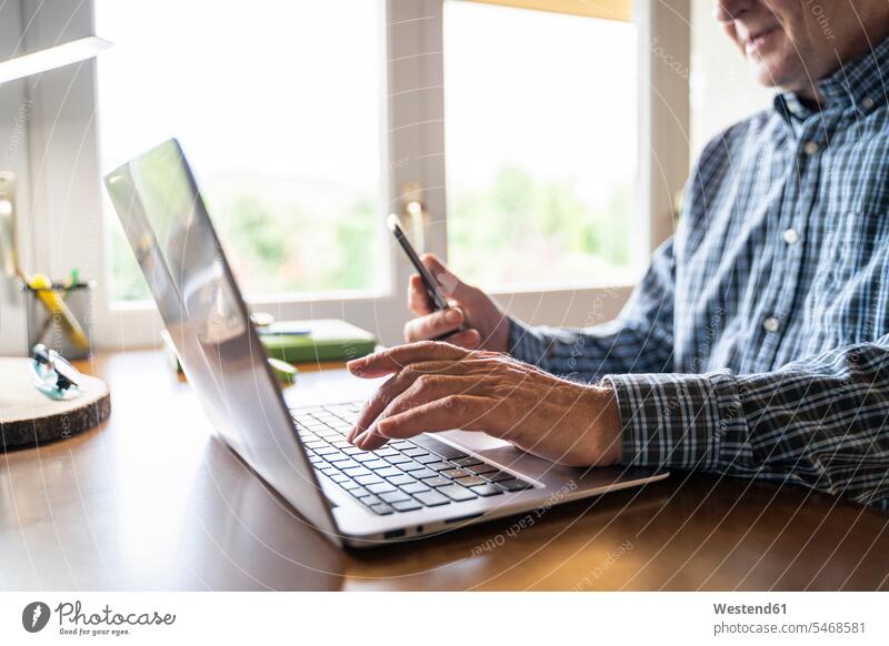 Senior man using laptop and smartphone at home human human being human beings humans person persons caucasian appearance caucasian ethnicity european 1