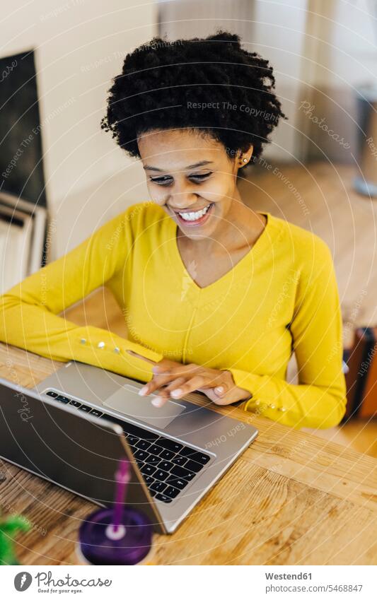 Young woman sitting at desk, using laptop home at home studying learning Surfing the Net Laptop Computers laptops notebook working At Work smiling smile