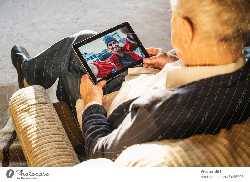 Grandfather talking with granddaughter on video call through digital tablet at home color image colour image indoors indoor shot indoor shots interior