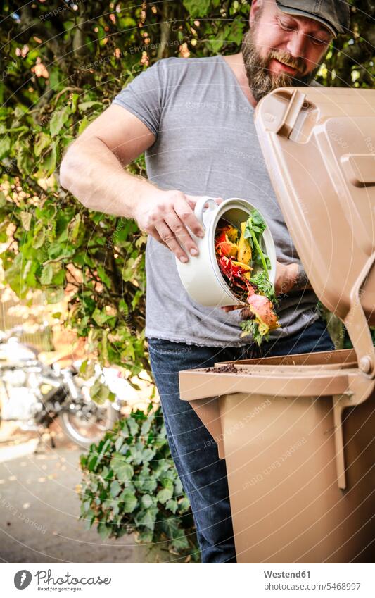 Mature man throwing kitchen scraps into bio-waste container kitchen waste garden gardens domestic garden mature men mature man males Adults grown-ups grownups