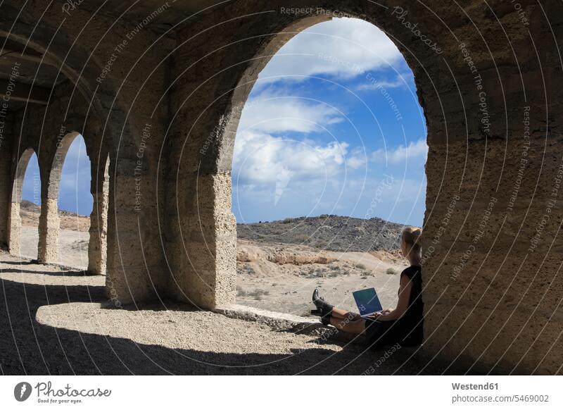 Spain, Tenerife, Abades, Sanatorio de Abona, woman sitting in ghost town building using laptop females women buildings Laptop Computers laptops notebook window