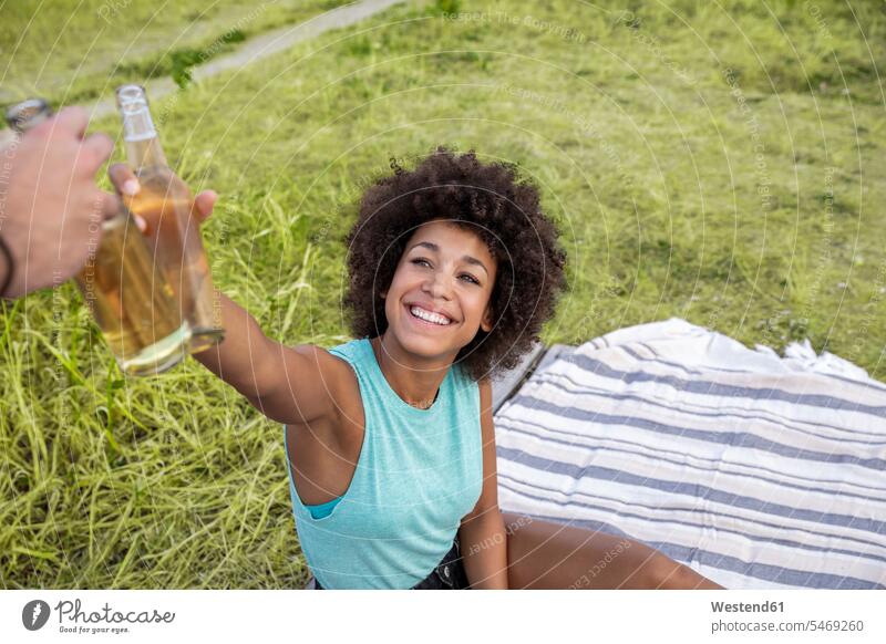 Happy woman sitting outdoors clinking beer bottle females women happiness happy toasting cheers couple twosomes partnership couples Seated Beer Beers Ale