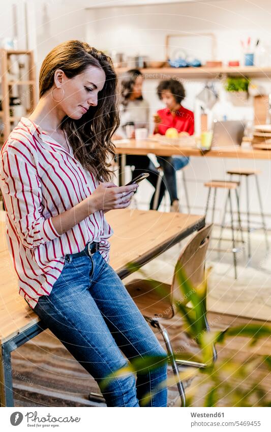 Woman with cell phone at table Table Tables mobile phone mobiles mobile phones Cellphone cell phones woman females women telephones communication