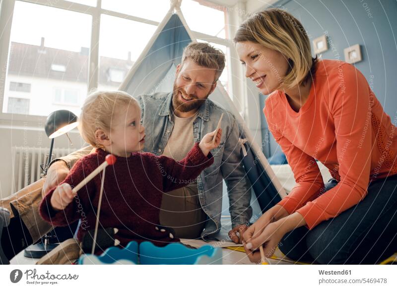 Happy family playing with their son at home families carefree gripping grabbing laughing Laughter camping toy toys tent tents happiness happy people persons