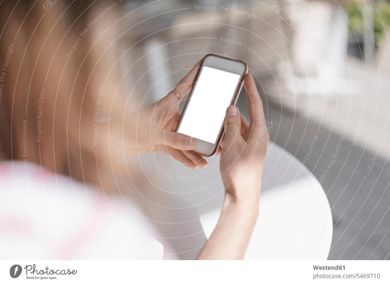 Young woman sitting in coffee shop, using smartphone use young women young woman Smartphone iPhone Smartphones cafe Seated females Adults grown-ups grownups