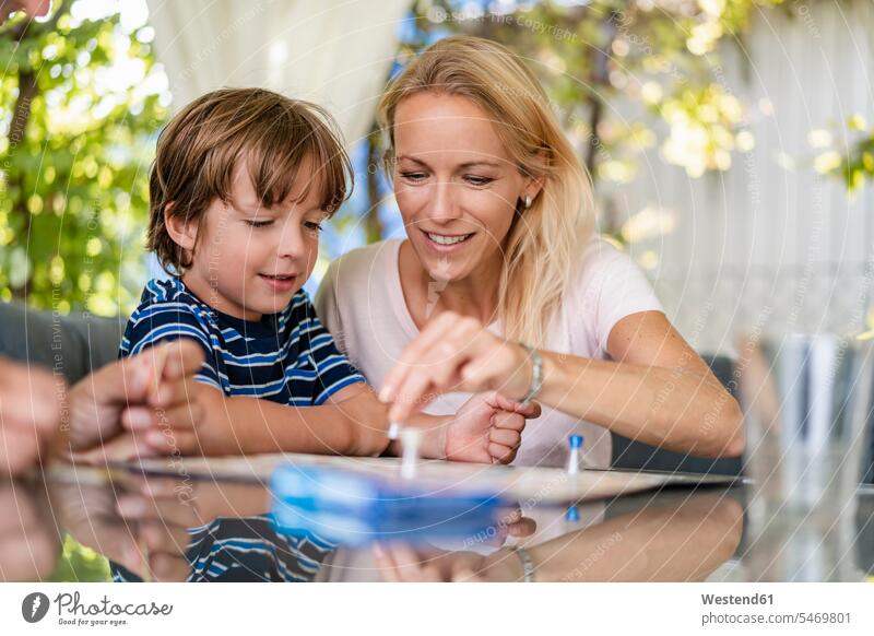 Mother and son playing a board game on terrace games parlor games parlour game parlour games board games board-game board-games boardgame smile Seated sit