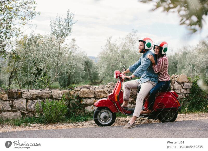 Couple exploring Tuscanyon Vespa, Italy color image colour image tourism touristic leisure activity leisure activities free time leisure time casual clothing