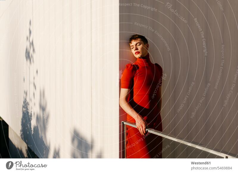 Gender fluid man standing against wall during sunset color image colour image outdoors location shots outdoor shot outdoor shots sunsets sundown atmosphere