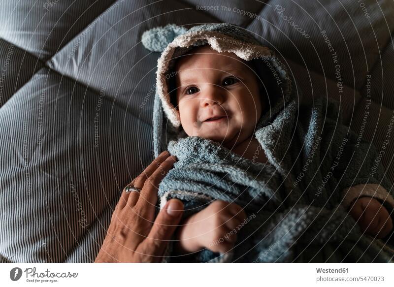 Portrait of baby girl lying on bed wrapped with shark shaped towel touched by mother's hand human human being human beings humans person persons